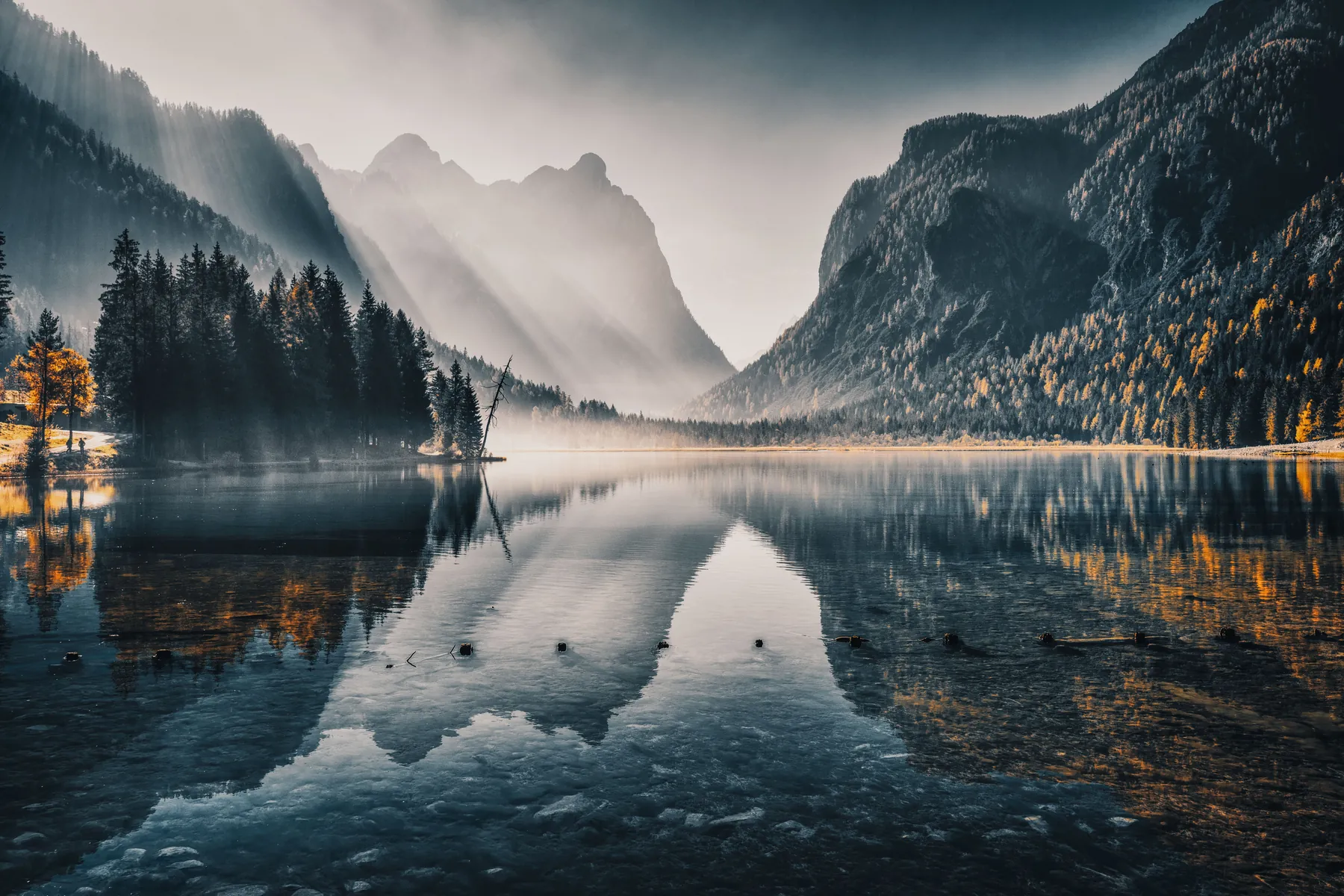 Lago en calma entre montañas cubiertas de niebla